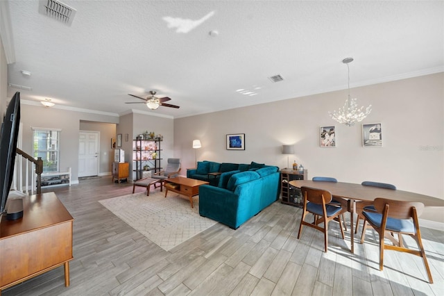 living room featuring baseboards, visible vents, ceiling fan with notable chandelier, and light wood-type flooring