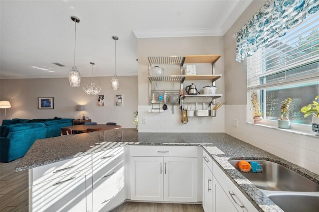 kitchen with crown molding, decorative backsplash, open shelves, and a peninsula