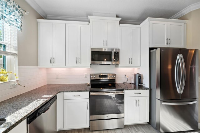 kitchen with crown molding, decorative backsplash, white cabinetry, and appliances with stainless steel finishes