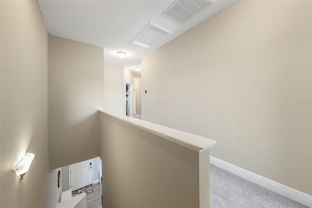 corridor with attic access, visible vents, baseboards, an upstairs landing, and carpet