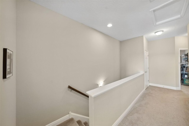 hallway with baseboards, carpet flooring, attic access, and an upstairs landing