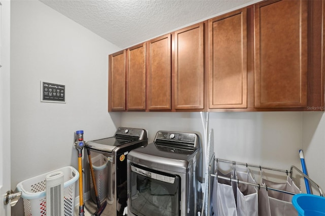 laundry room with a textured ceiling, cabinet space, and washer and dryer