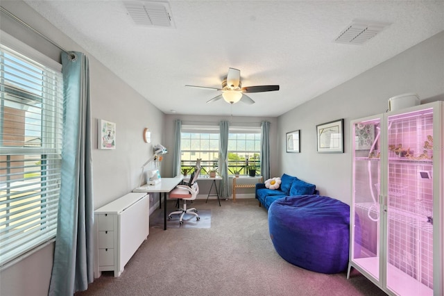 carpeted office featuring a ceiling fan and visible vents