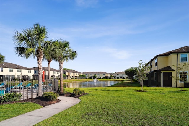 surrounding community with a lawn, a water view, fence, and a residential view