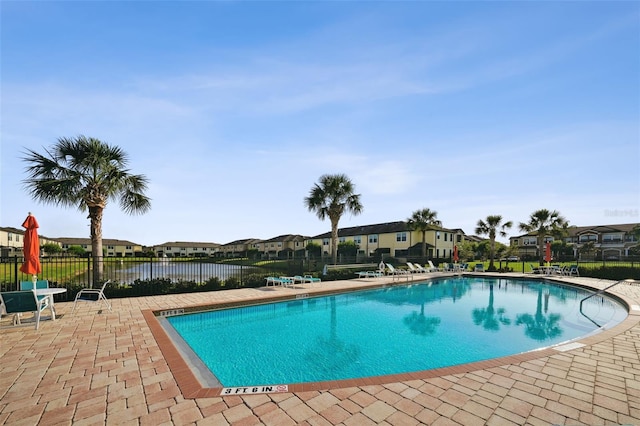 community pool with a patio, fence, and a residential view