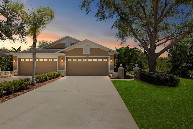 view of front of home featuring driveway, a front yard, stucco siding, and an attached garage