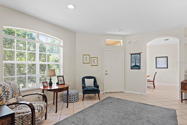 sitting room with baseboards, recessed lighting, light tile patterned floors, and arched walkways
