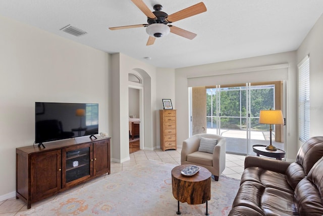 living room with visible vents, light tile patterned floors, a wealth of natural light, and arched walkways