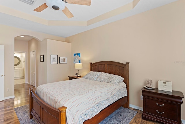 bedroom featuring baseboards, visible vents, arched walkways, and wood finished floors