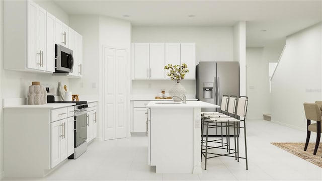 kitchen with a kitchen breakfast bar, an island with sink, light countertops, appliances with stainless steel finishes, and white cabinetry