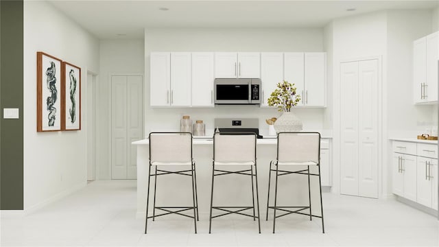 kitchen featuring white cabinets, a kitchen breakfast bar, a center island, and appliances with stainless steel finishes