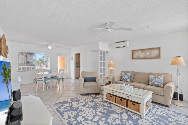 living room with a wall mounted air conditioner, a ceiling fan, and light tile patterned floors