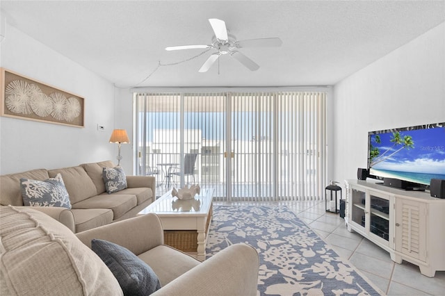 living room with a ceiling fan, light tile patterned flooring, and a textured ceiling