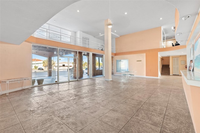 interior space with recessed lighting, baseboards, a towering ceiling, and stairs