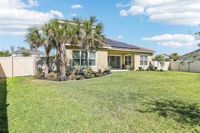 3952 Bonfire Dr, Odessa, FL 33556 - back of house with a gate, stucco siding, a lawn, solar panels, and a fenced backyard