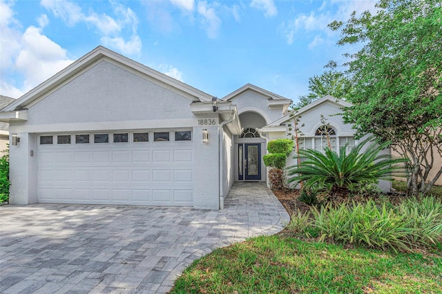 view of front of home with decorative driveway, a garage, and stucco siding