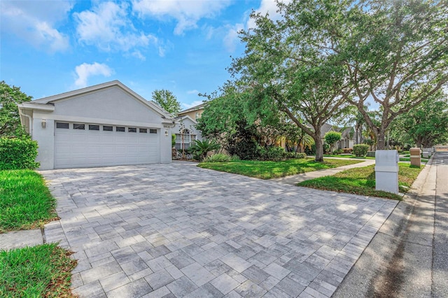 ranch-style house featuring a garage, stucco siding, a front lawn, and decorative driveway