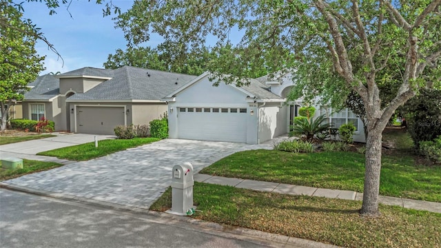 view of front of home with a front yard, a garage, decorative driveway, a shingled roof, and stucco siding