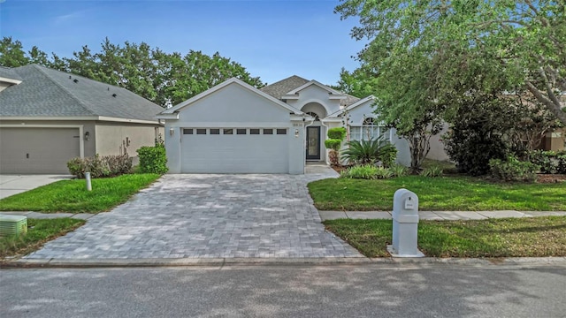 single story home featuring decorative driveway, an attached garage, a front lawn, and stucco siding