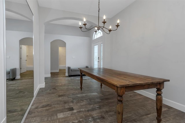 dining room with arched walkways, baseboards, and dark wood finished floors