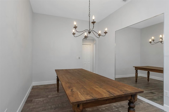 dining space featuring baseboards, arched walkways, dark wood finished floors, and a chandelier