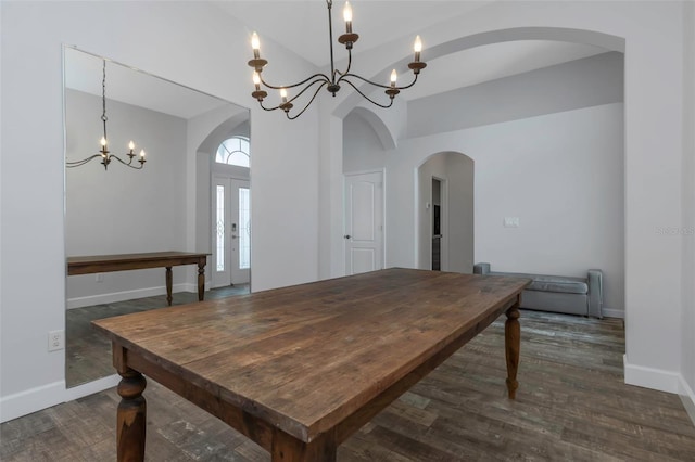 dining space featuring arched walkways, baseboards, dark wood-type flooring, and a notable chandelier