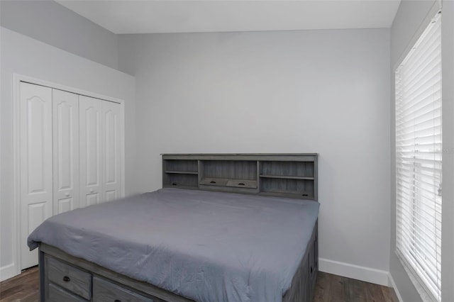 bedroom with a closet, baseboards, and dark wood-type flooring