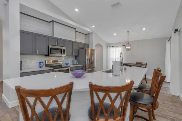 kitchen featuring arched walkways, light wood-style flooring, a breakfast bar area, and stainless steel appliances