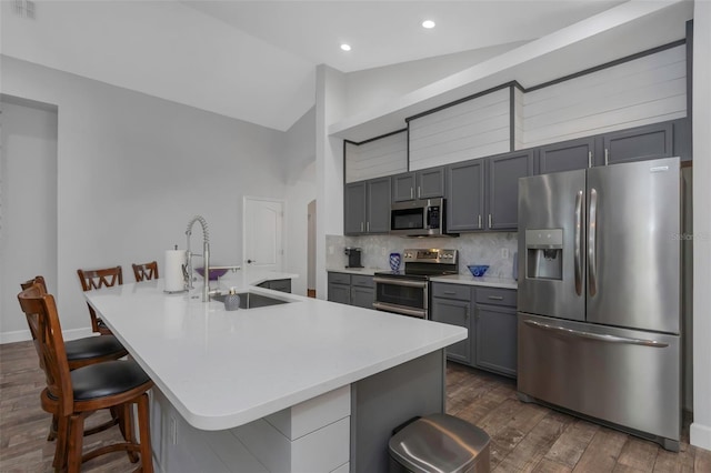 kitchen featuring dark wood-style flooring, vaulted ceiling, a sink, light countertops, and stainless steel appliances
