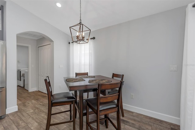 dining area with baseboards, arched walkways, wood finished floors, and washer and clothes dryer