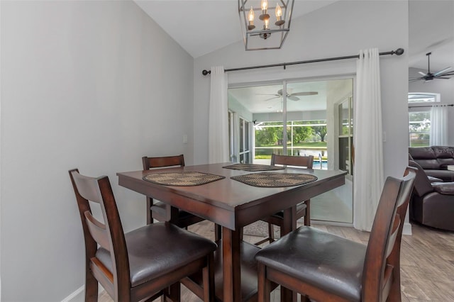 dining space with plenty of natural light, ceiling fan with notable chandelier, light wood-type flooring, and lofted ceiling