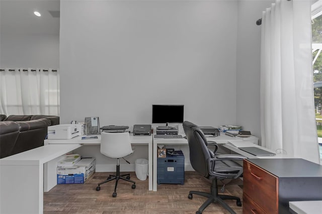 office with wood finished floors and a towering ceiling