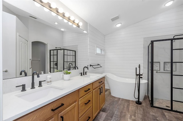 full bathroom featuring vaulted ceiling, a sink, visible vents, and wood finished floors