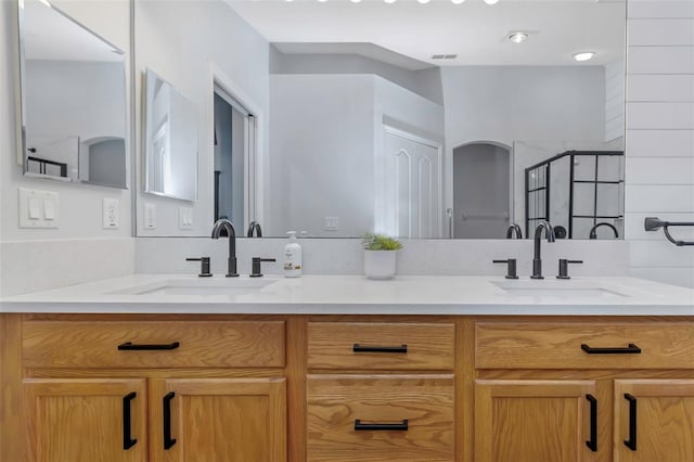 full bathroom featuring visible vents, a sink, double vanity, and a shower stall
