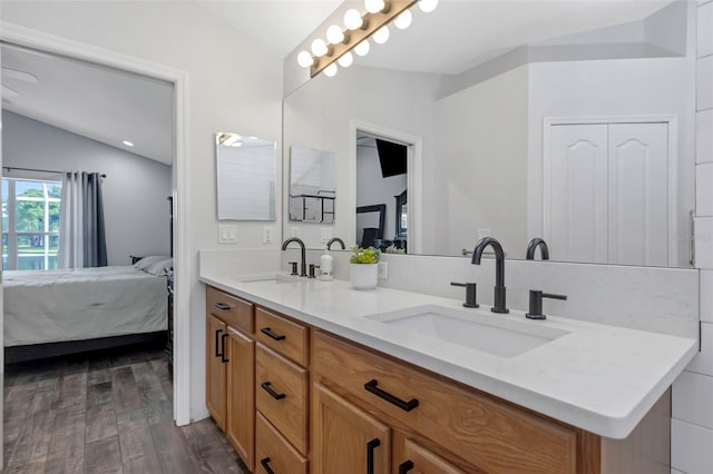 full bathroom featuring a sink, ensuite bathroom, vaulted ceiling, and wood finished floors
