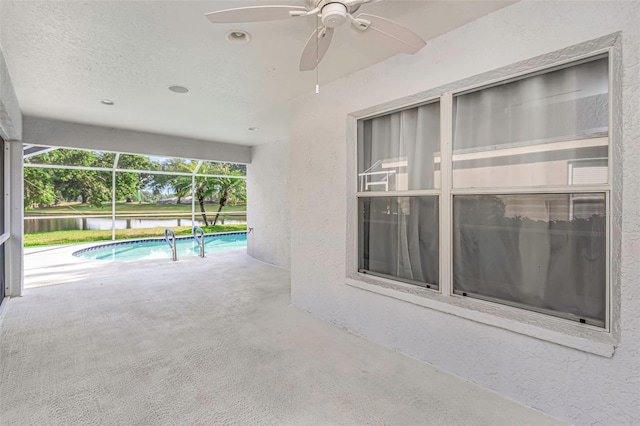 pool featuring glass enclosure, a ceiling fan, and a patio area