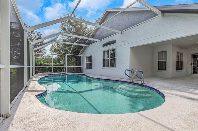 view of swimming pool featuring glass enclosure, a pool with connected hot tub, and a patio area