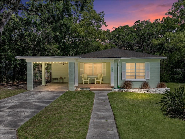 131 Oak Park Ave, Brooksville, FL 34601 - view of front of house featuring a lawn, driveway, concrete block siding, covered porch, and an attached carport