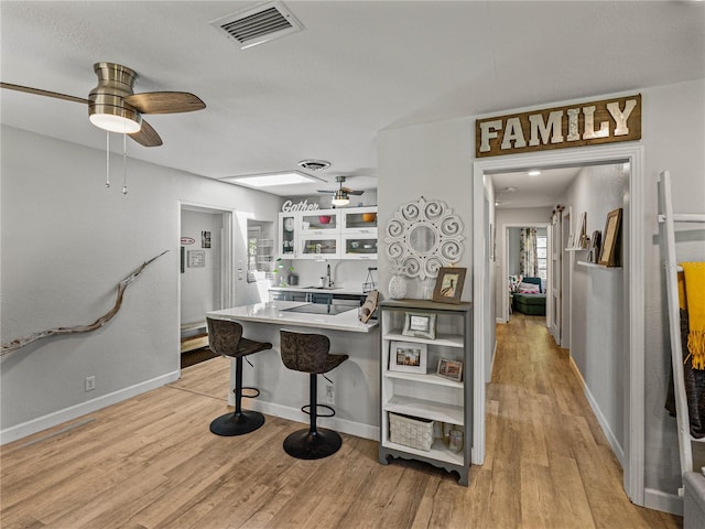 131 Oak Park Ave, Brooksville, FL 34601 - kitchen with a breakfast bar, visible vents, a ceiling fan, a peninsula, and glass insert cabinets