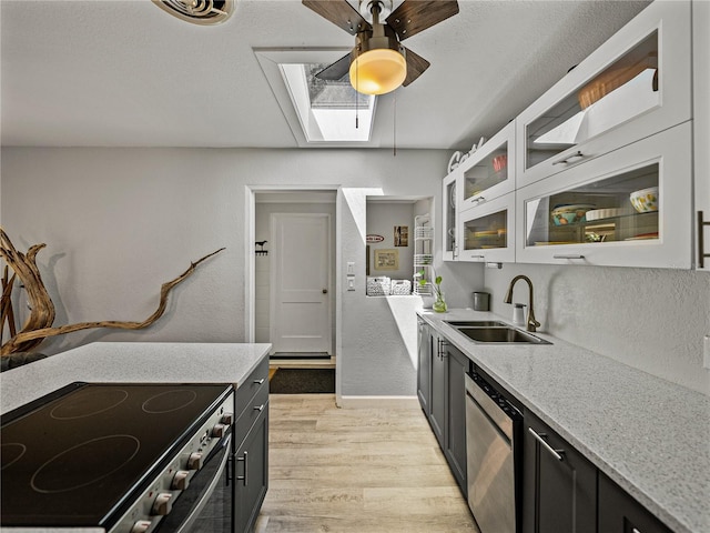 131 Oak Park Ave, Brooksville, FL 34601 - kitchen featuring light wood finished floors, stainless steel appliances, a sink, a skylight, and ceiling fan