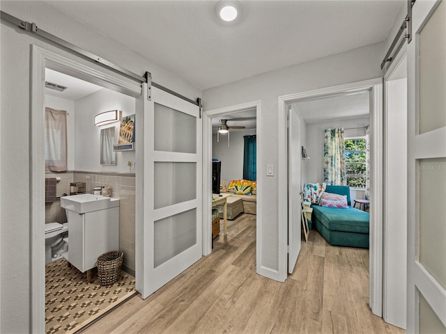 131 Oak Park Ave, Brooksville, FL 34601 - hall with a barn door, light wood-style floors, tile walls, and visible vents