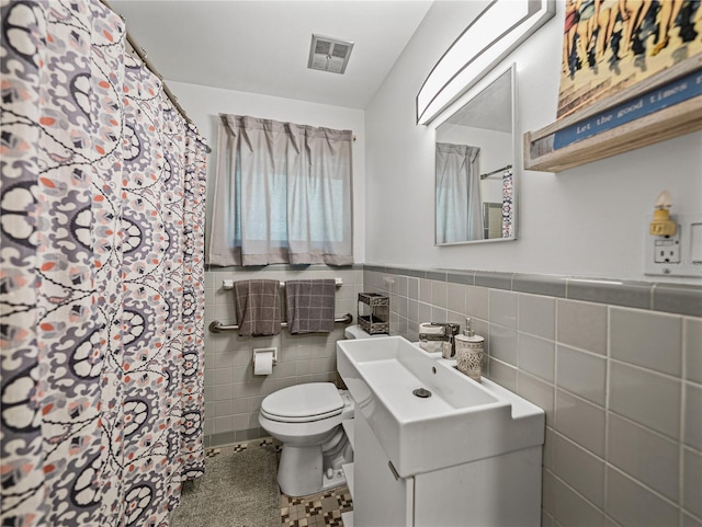 131 Oak Park Ave, Brooksville, FL 34601 - full bathroom featuring visible vents, toilet, vanity, tile walls, and wainscoting