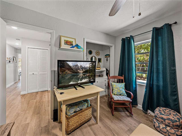 131 Oak Park Ave, Brooksville, FL 34601 - living area with baseboards, a ceiling fan, a textured ceiling, and light wood-style floors