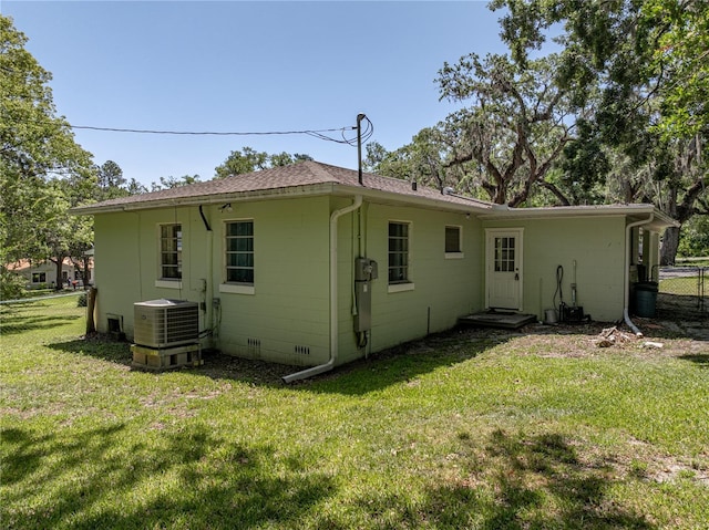 131 Oak Park Ave, Brooksville, FL 34601 - back of house with central AC unit, fence, concrete block siding, a lawn, and roof with shingles