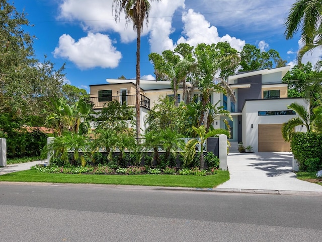 view of front of home featuring concrete driveway, an attached garage, a balcony, and stucco siding