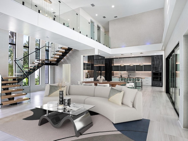 living area featuring stairway, a high ceiling, and recessed lighting
