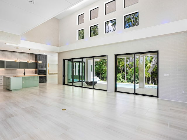 unfurnished living room with light tile patterned floors, a high ceiling, and a wealth of natural light