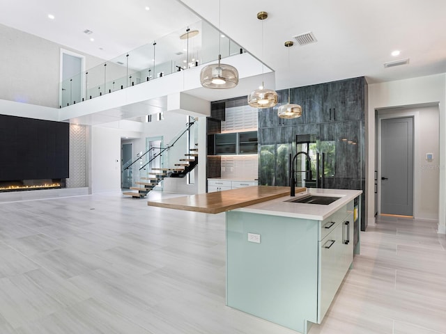 kitchen featuring a sink, open floor plan, a spacious island, a fireplace, and visible vents