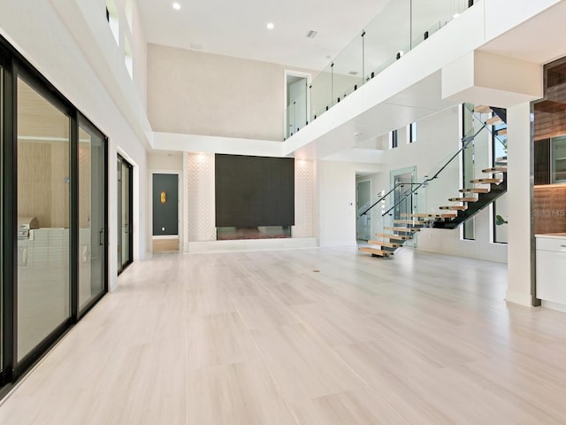 unfurnished living room featuring a fireplace, a towering ceiling, and stairs