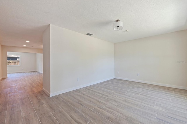 unfurnished room with baseboards, visible vents, and light wood-style floors